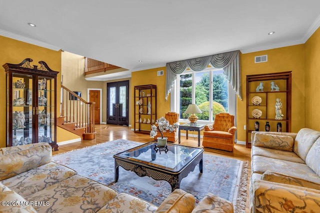 living area with baseboards, ornamental molding, wood finished floors, and stairway