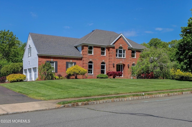 colonial house with a garage, a front lawn, and brick siding