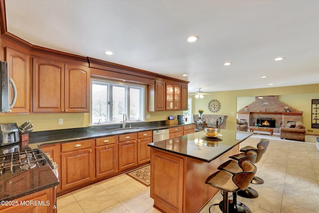 kitchen with a breakfast bar, a sink, light tile patterned flooring, a kitchen island, and a fireplace