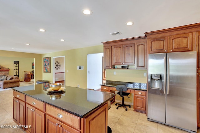 kitchen with stainless steel refrigerator with ice dispenser, a kitchen island, recessed lighting, light tile patterned floors, and open floor plan
