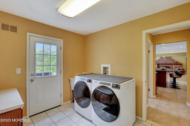 clothes washing area with light tile patterned floors, washer and clothes dryer, and baseboards