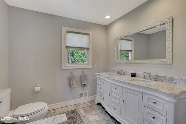 bathroom featuring toilet, marble finish floors, baseboards, double vanity, and recessed lighting