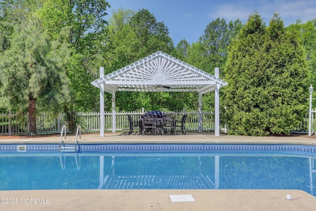 view of pool featuring fence, outdoor dining space, a pergola, and view of wooded area