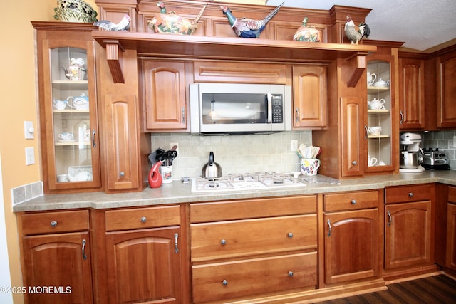 397 Finch Way, Freehold, NJ 07728 - kitchen featuring stainless steel microwave, white gas cooktop, tasteful backsplash, glass insert cabinets, and brown cabinets