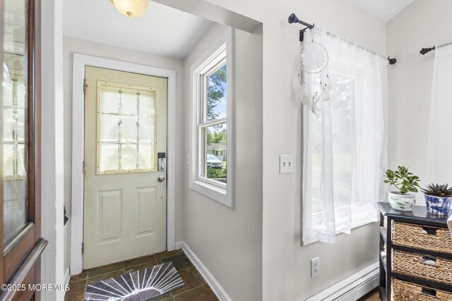 doorway to outside featuring baseboards and dark tile patterned flooring