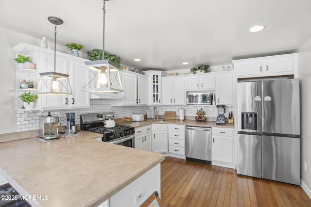 kitchen featuring light countertops, a sink, a peninsula, stainless steel appliances, and wall chimney exhaust hood