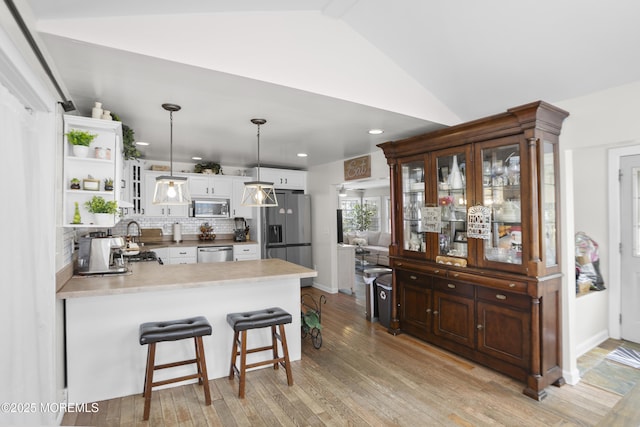 kitchen with open shelves, a peninsula, light wood-type flooring, white cabinetry, and stainless steel appliances