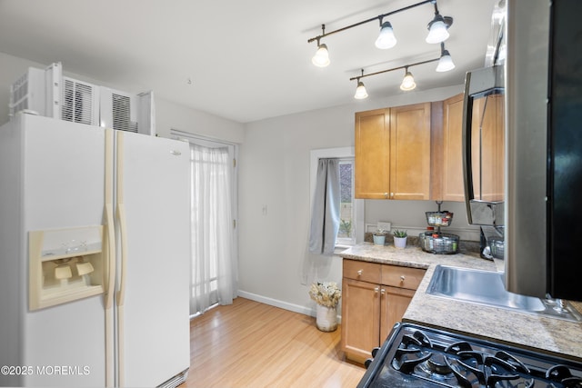 kitchen with white refrigerator with ice dispenser, light countertops, baseboards, gas stove, and light wood-style flooring