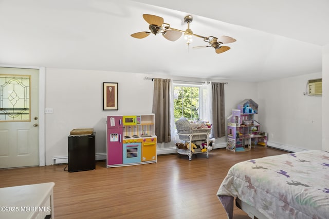 bedroom featuring baseboard heating, a baseboard heating unit, and wood finished floors