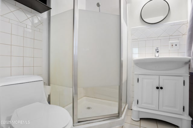 full bath featuring tile patterned flooring, vanity, toilet, tile walls, and a shower stall