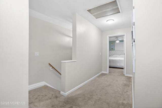 hallway featuring light colored carpet, visible vents, an upstairs landing, and baseboards