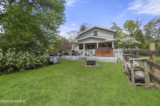 back of house with a fire pit, a yard, and fence