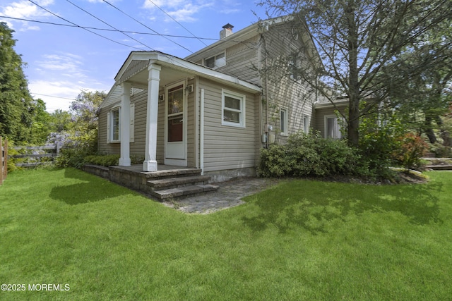 view of side of home with a yard, a chimney, and fence