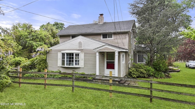 view of front of home featuring roof with shingles, fence, a chimney, and a front yard