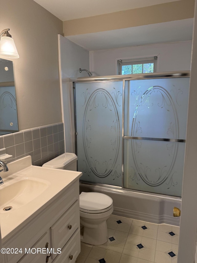 full bathroom with vanity, toilet, tile patterned floors, tile walls, and combined bath / shower with glass door