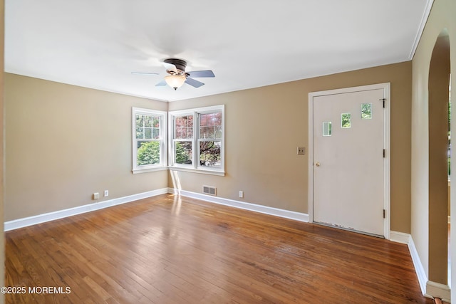 unfurnished room with arched walkways, ceiling fan, baseboards, and hardwood / wood-style floors