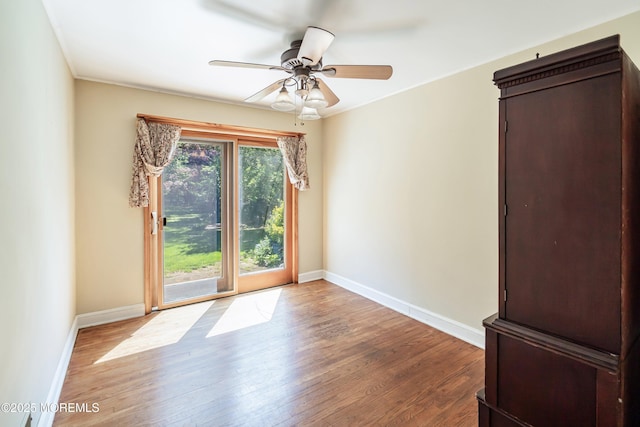 empty room featuring wood finished floors, baseboards, and ceiling fan