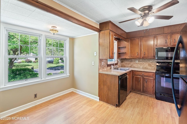 kitchen with black appliances, a sink, light countertops, brown cabinetry, and light wood-style flooring