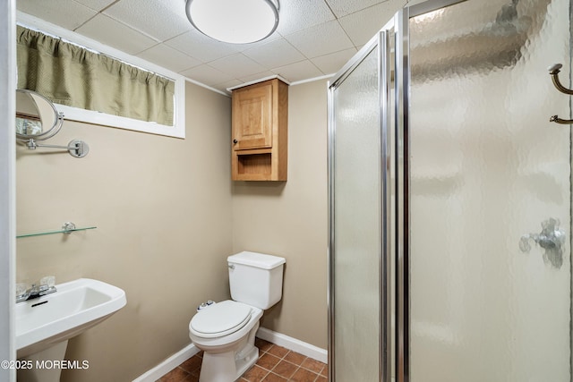 full bath featuring a shower stall, baseboards, tile patterned floors, toilet, and a sink