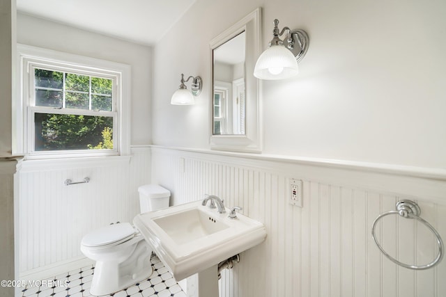 bathroom with wainscoting, toilet, and a sink