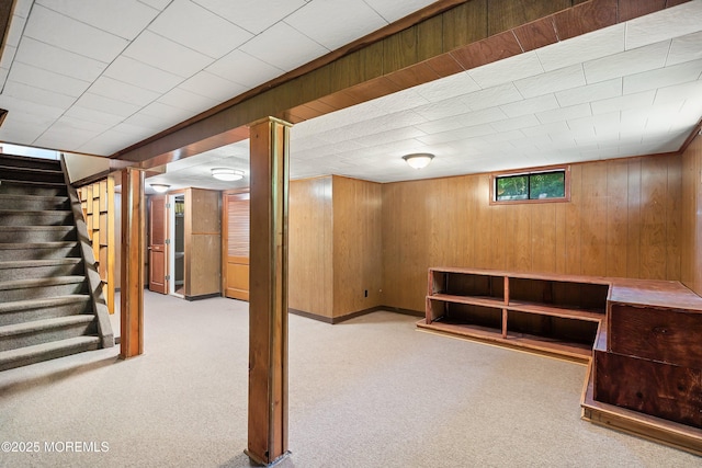 below grade area featuring stairs, carpet, and wooden walls