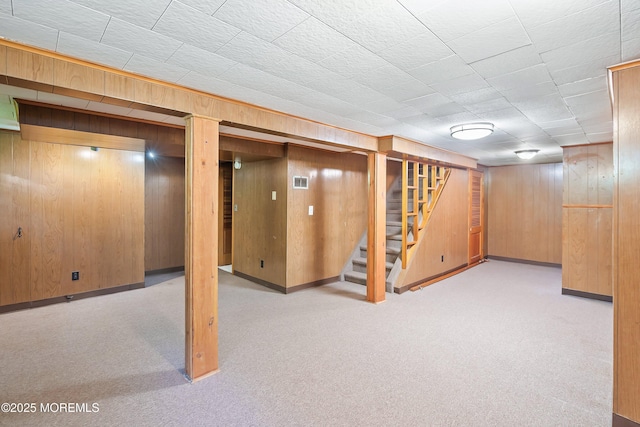 finished below grade area featuring wood walls, stairs, and light carpet