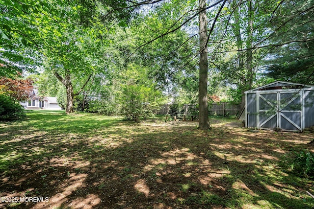 view of yard featuring fence, a storage unit, and an outdoor structure