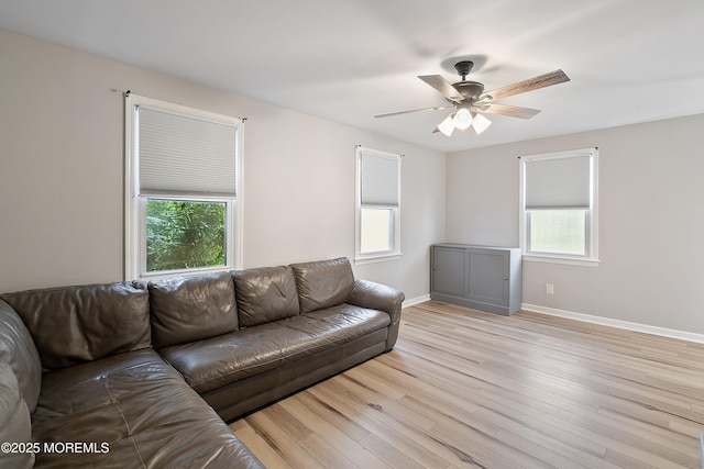 living room with ceiling fan, light wood-style floors, and baseboards