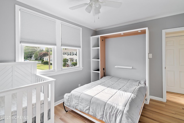 bedroom featuring crown molding, wood finished floors, baseboards, and a ceiling fan