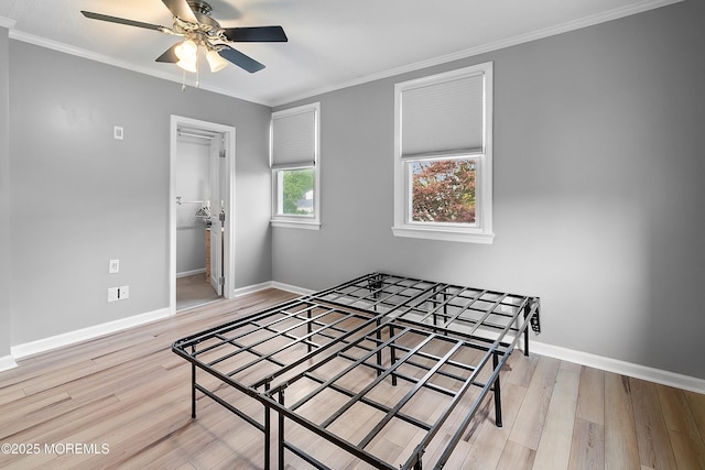 bedroom with wood finished floors, baseboards, crown molding, a ceiling fan, and a spacious closet