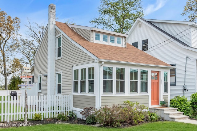 bungalow featuring fence, a chimney, and roof with shingles