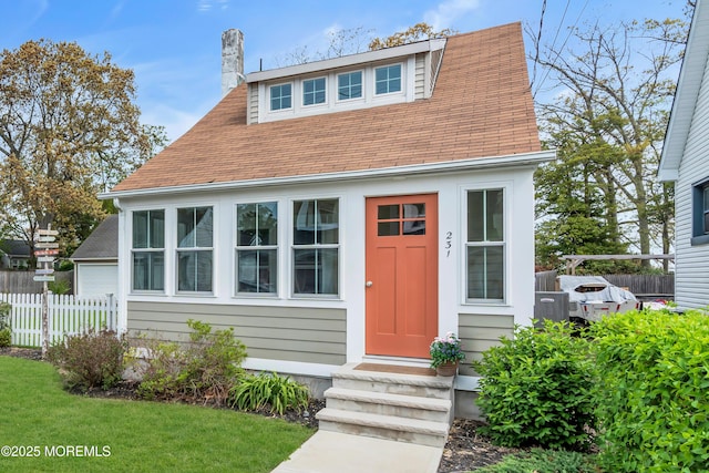 bungalow-style house with fence, a chimney, entry steps, and roof with shingles