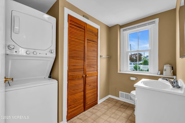 laundry room featuring visible vents, laundry area, baseboards, a sink, and stacked washer / drying machine