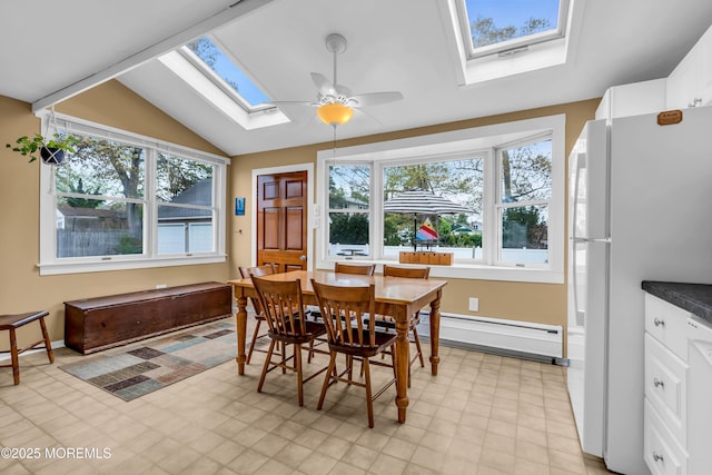 dining room with a healthy amount of sunlight, light floors, a baseboard radiator, and vaulted ceiling with skylight