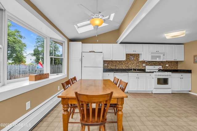 kitchen featuring dark countertops, white appliances, lofted ceiling with skylight, a baseboard radiator, and a ceiling fan