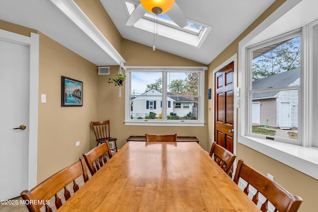 dining area with a ceiling fan, visible vents, plenty of natural light, and vaulted ceiling with skylight