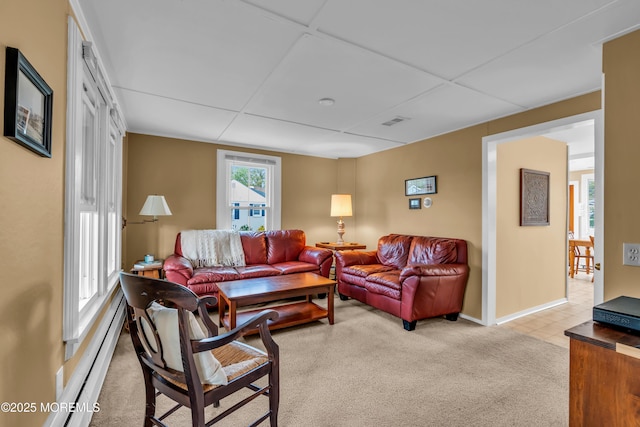 living area featuring light colored carpet, baseboards, a baseboard heating unit, and visible vents
