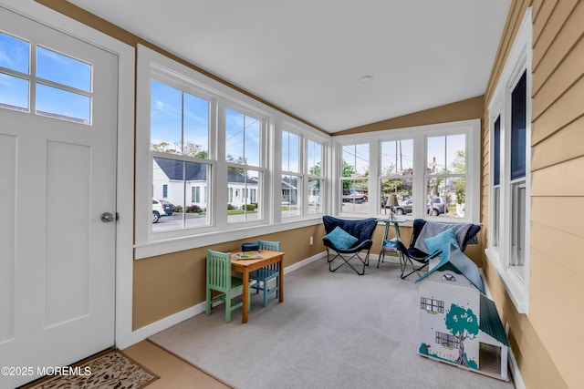 sunroom with a healthy amount of sunlight, baseboards, carpet, and vaulted ceiling