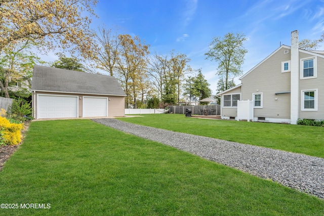 view of yard with fence, an outbuilding, and a garage