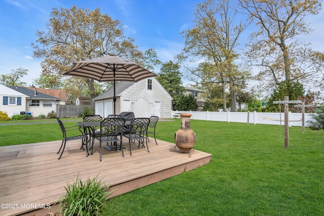 deck with a lawn, fence, outdoor dining area, and a detached garage
