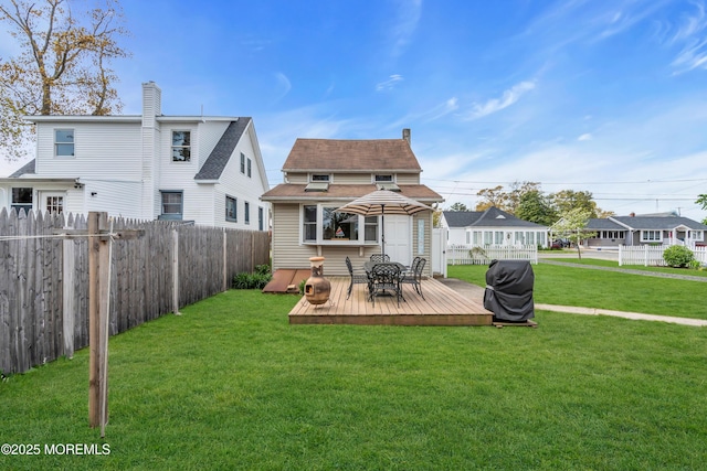 back of house featuring a fenced backyard, a shingled roof, a lawn, and a deck