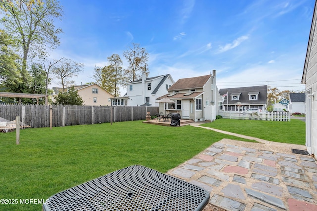 view of yard featuring a fenced backyard, a wooden deck, a residential view, and a patio