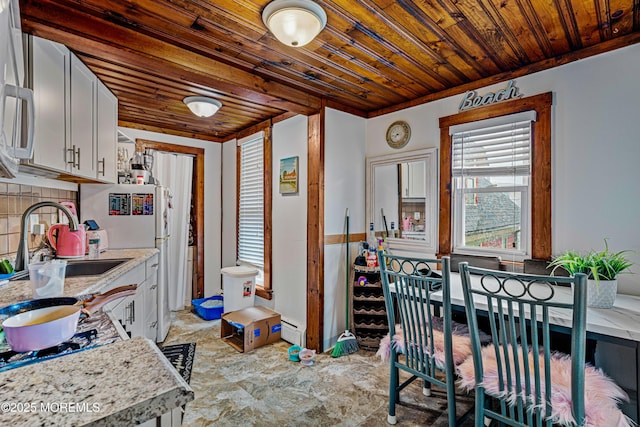 kitchen featuring baseboard heating, wooden ceiling, a sink, white cabinetry, and decorative backsplash