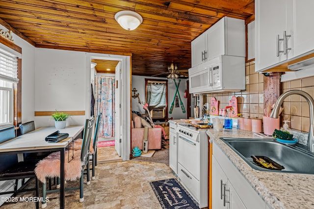 kitchen featuring a sink, stone finish floor, white cabinets, white appliances, and wooden ceiling