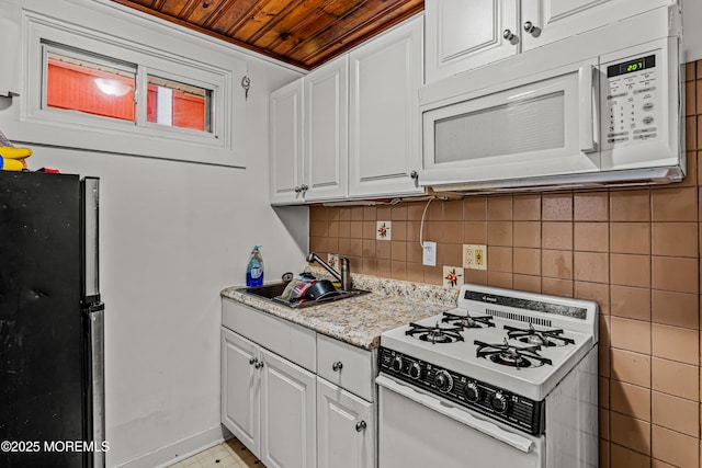 kitchen featuring wooden ceiling, tasteful backsplash, white appliances, a sink, and white cabinets