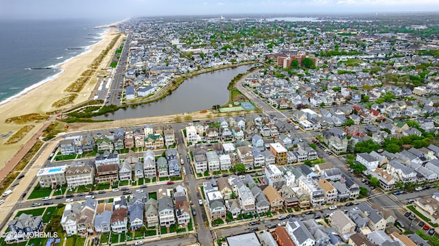drone / aerial view featuring a view of the beach, a water view, and a residential view