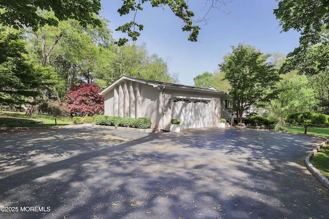 view of property exterior with an attached garage and driveway