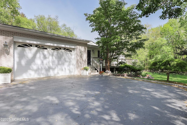 single story home featuring driveway, brick siding, and an attached garage