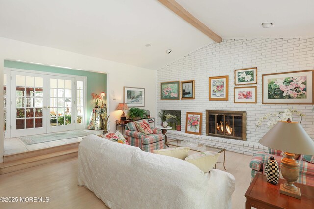 living room featuring light wood finished floors, french doors, a brick fireplace, brick wall, and vaulted ceiling with beams