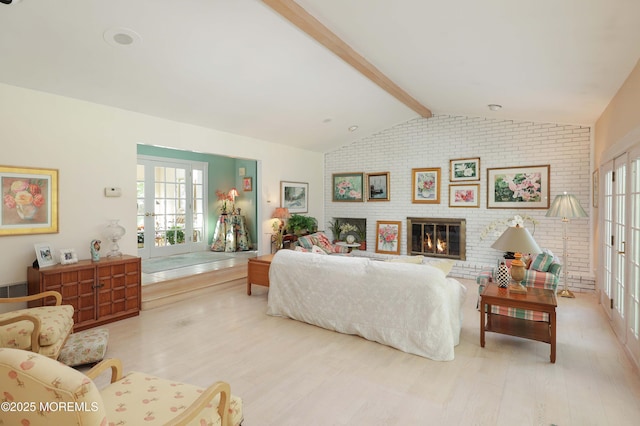 living room with brick wall, light wood-style flooring, a brick fireplace, and a healthy amount of sunlight